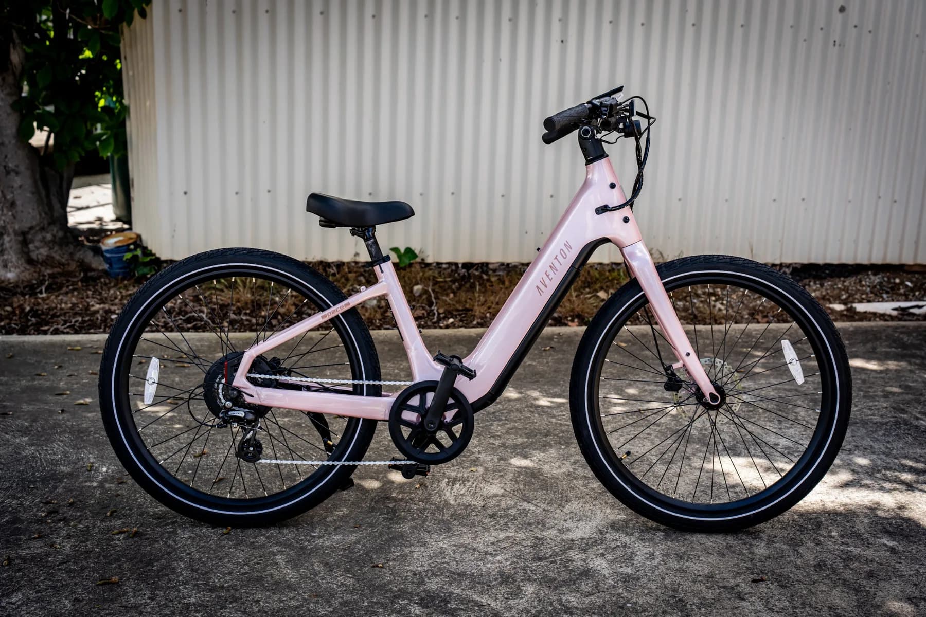 Pink Aventon Pace 5 REC ST step-through e-bike side profile against a white corrugated wall