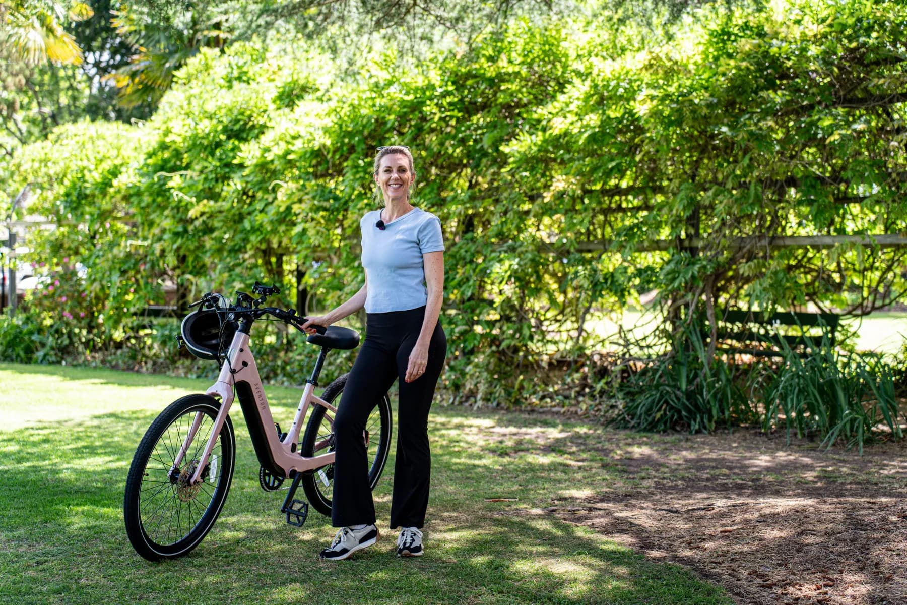 Presenter standing beside a pink Aventon Pace 5 REC ST in a leafy garden