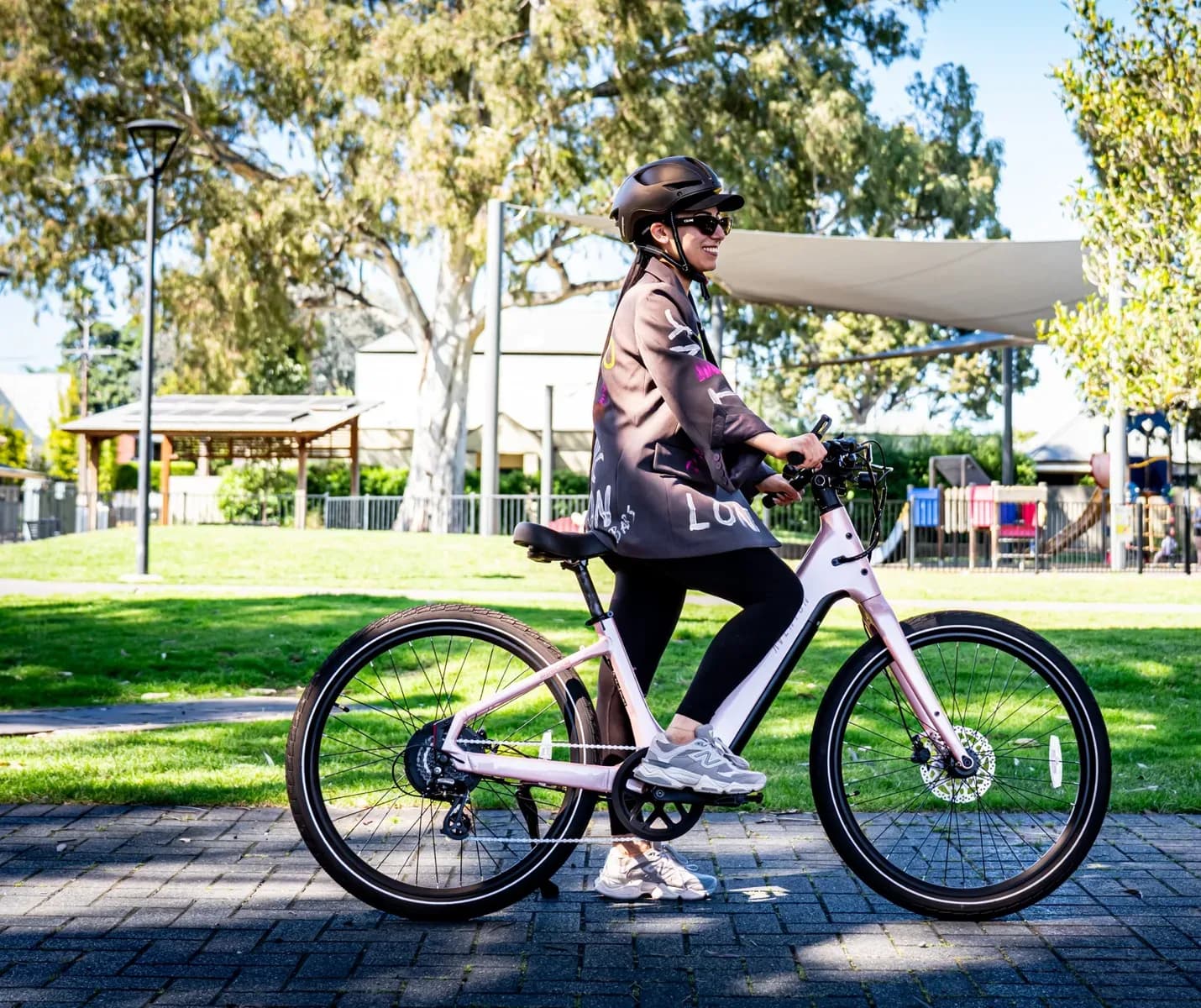 Rider sitting upright on a pink Aventon Pace 5 REC ST on a paved path in a park